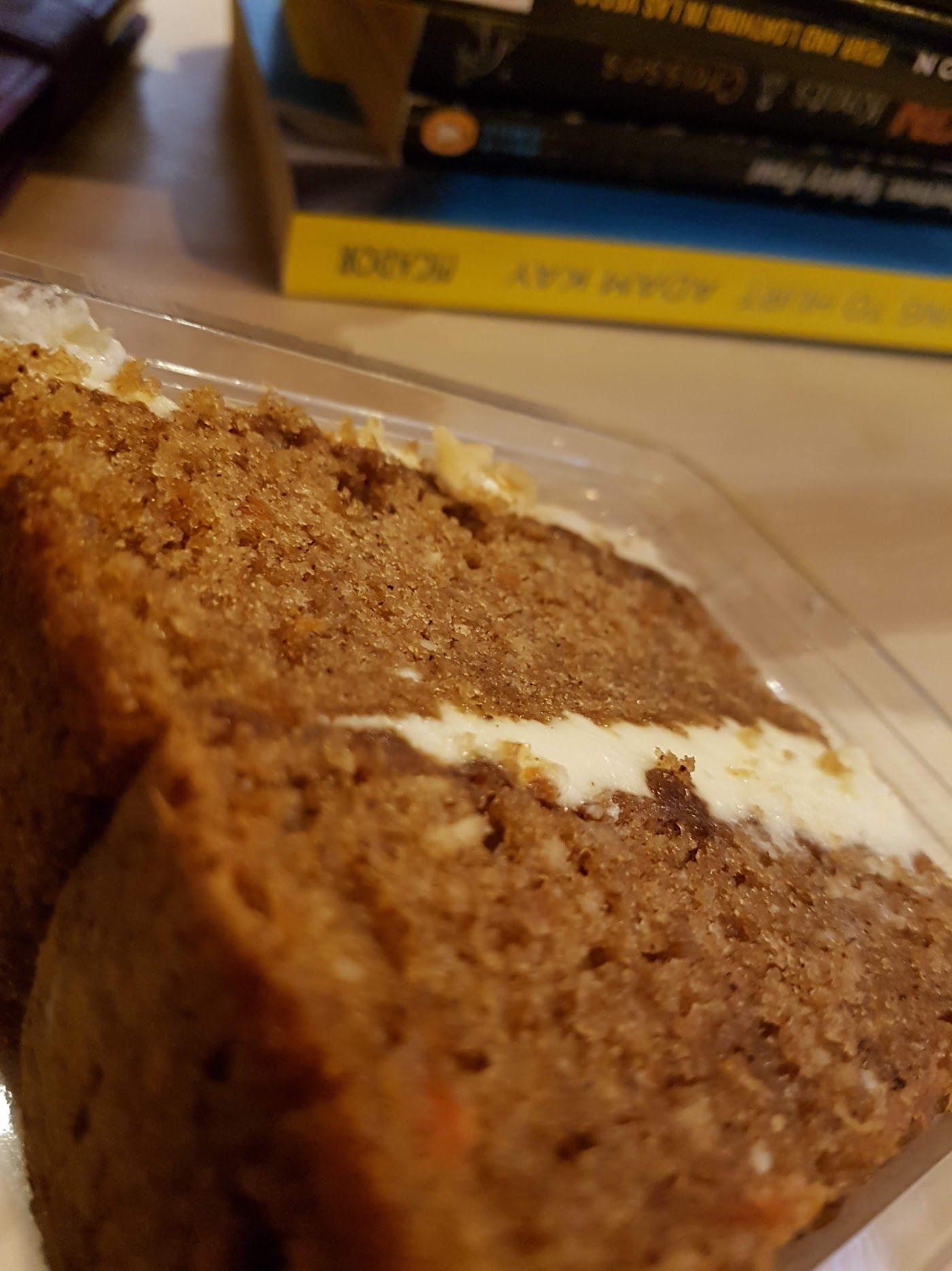 A thick slice of carrot cake with a layer of cream cheese frosting.