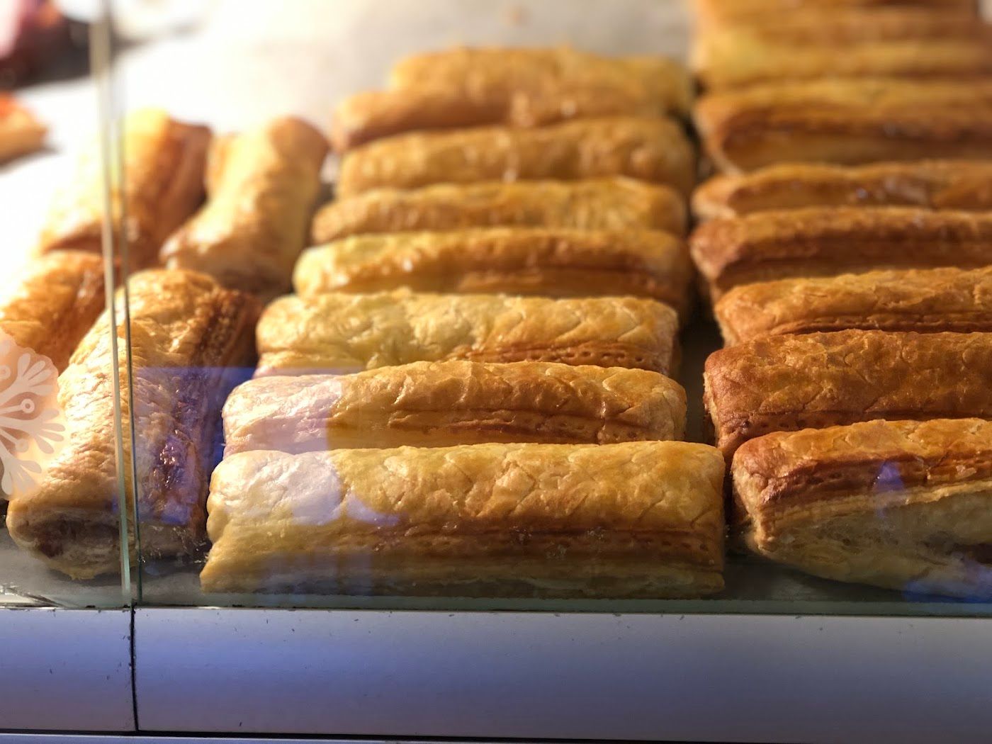Rows of golden, flaky sausage rolls in the bakery counter.
